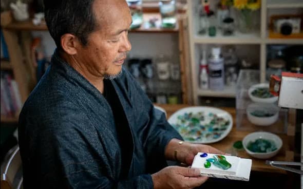 An artisan holding pieces of sea glass